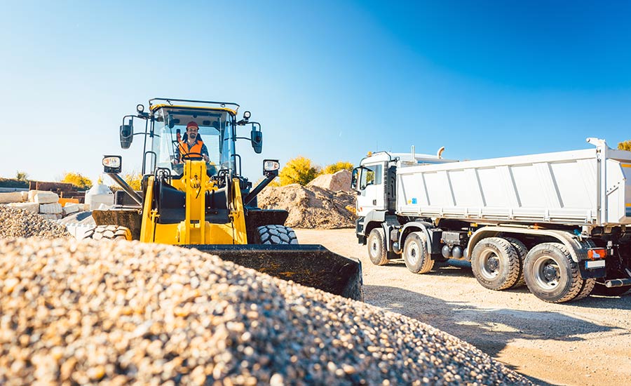 Bauarbeiter bei Erdarbeiten mit Radlader und Bauschutt LKW