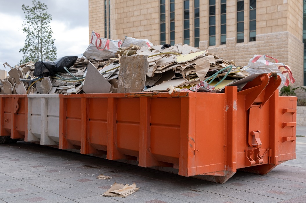 riesiger Haufen auf Metall Großer überladener Müllcontainer, gefüllt mit Bauschutt, Trockenbauwänden und anderem Schutt in der Nähe einer Baustelle.